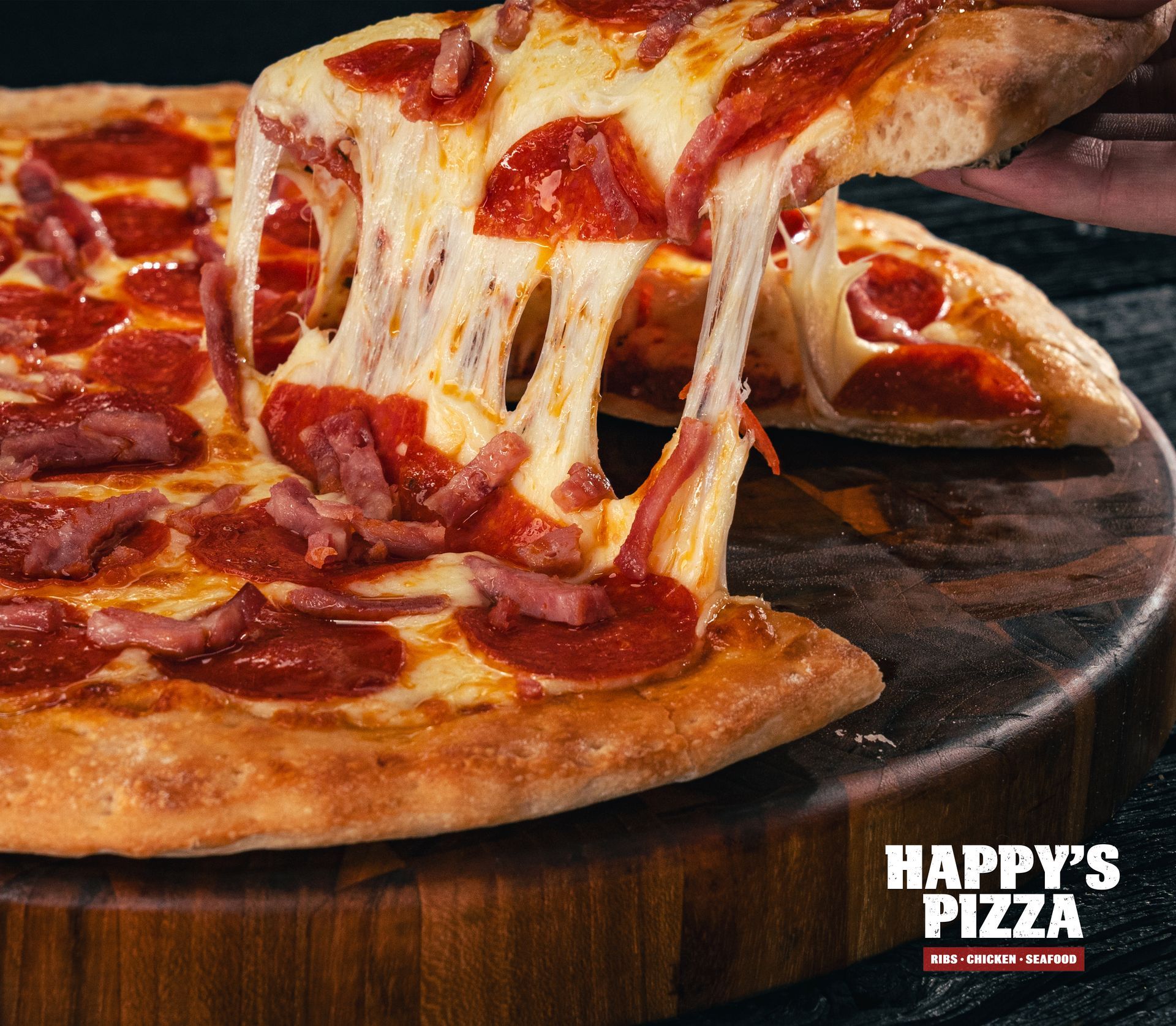 A person is taking a slice of pepperoni pizza from happy 's pizza