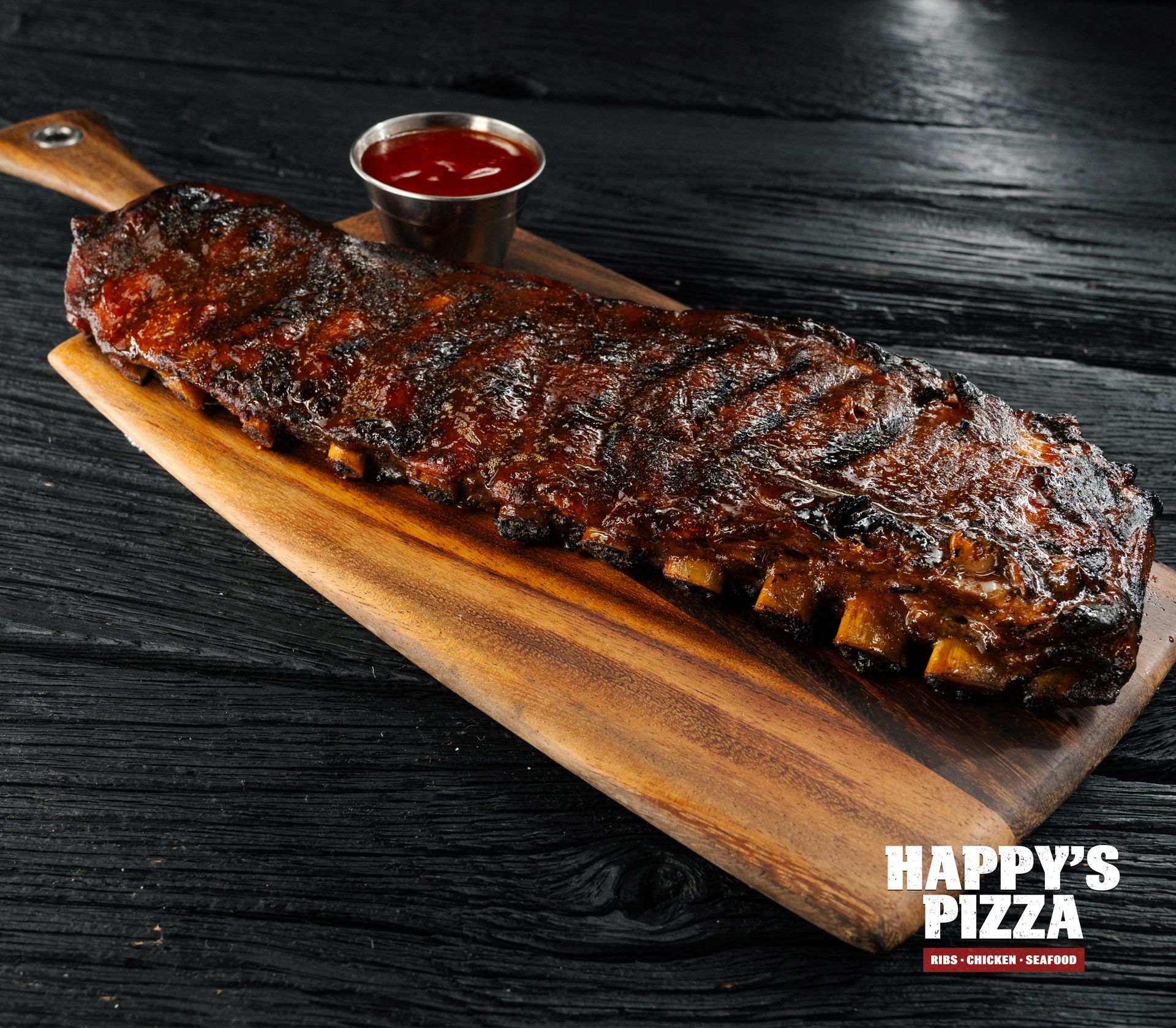 A wooden cutting board with ribs and ketchup on it from happy 's pizza