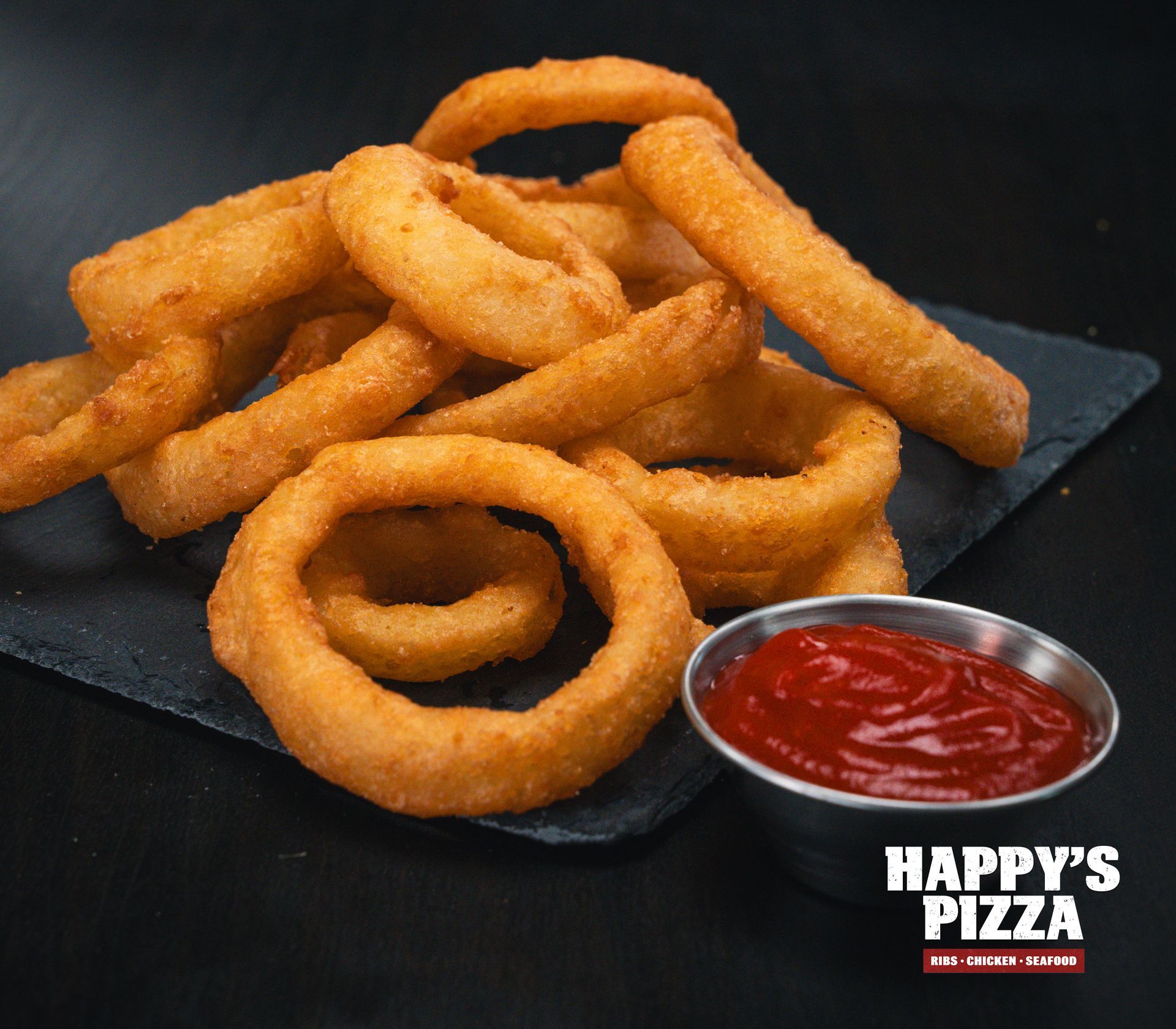 A plate of onion rings with ketchup from happy 's pizza