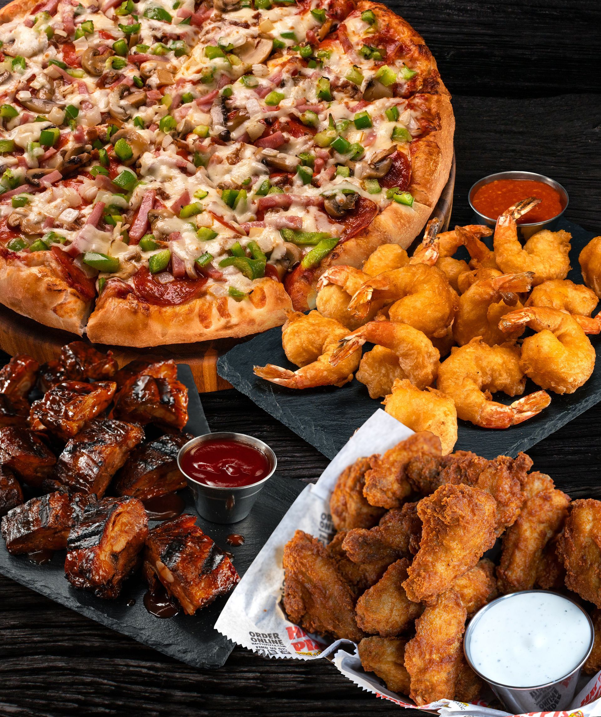 A pizza , shrimp , and chicken wings are on a table.