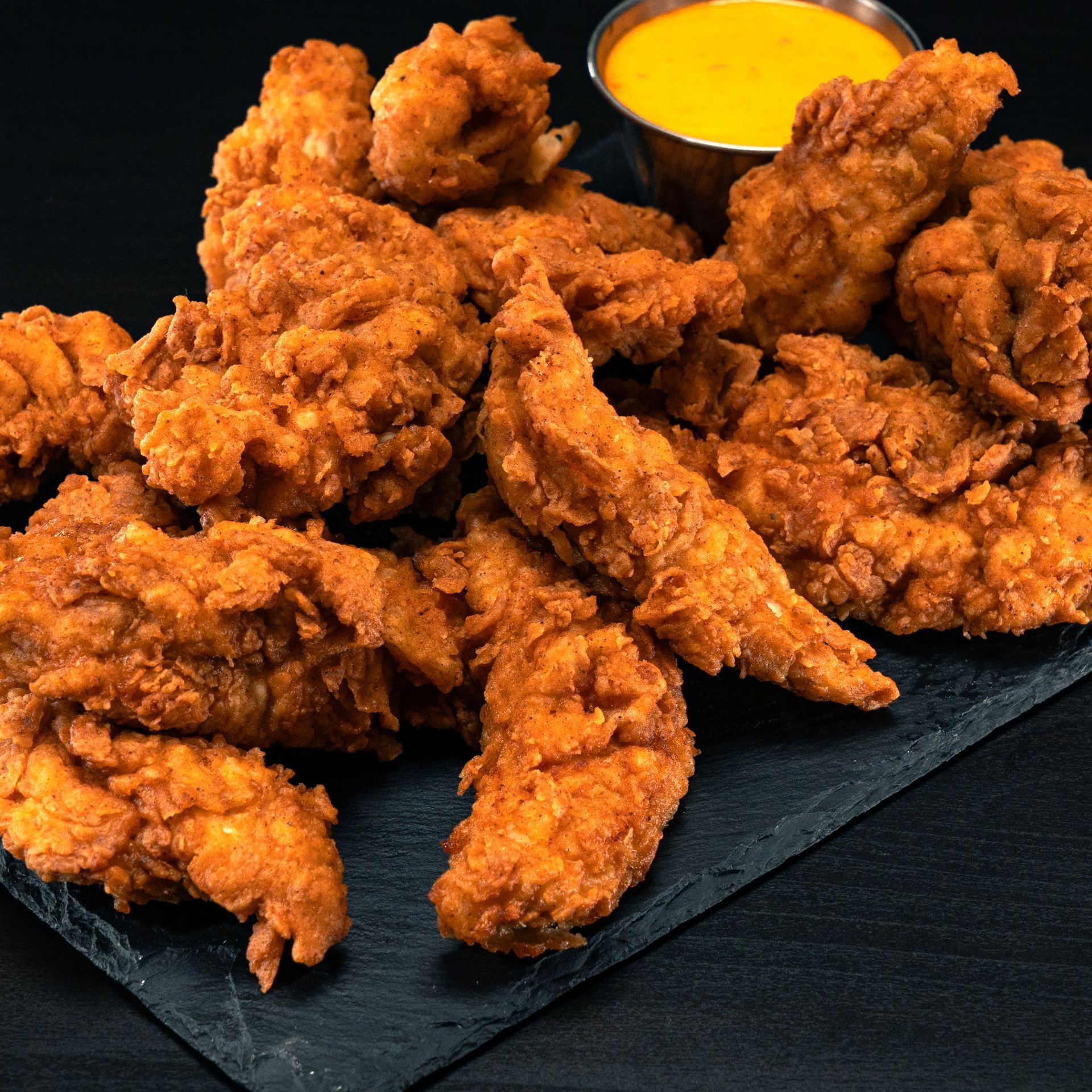 Golden fried chicken tenders served in a large portion, perfect for catering events or sharing.