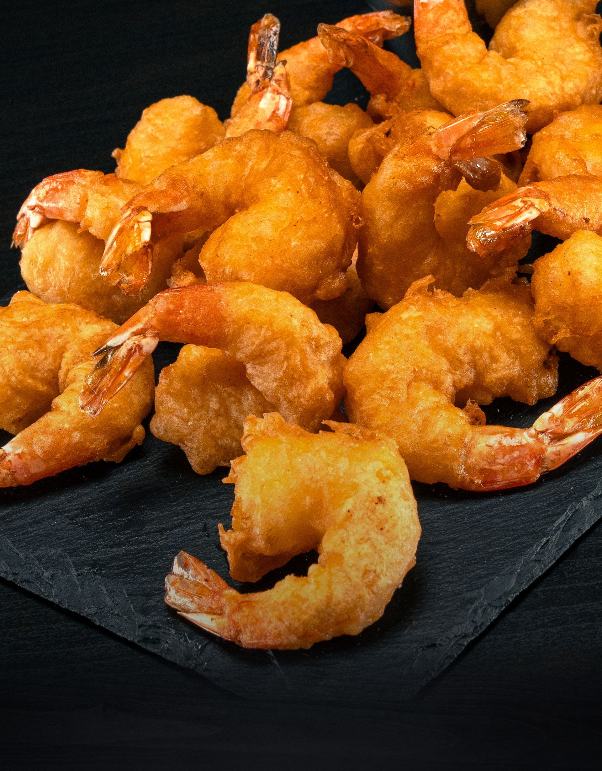 A pile of fried shrimp on a black plate