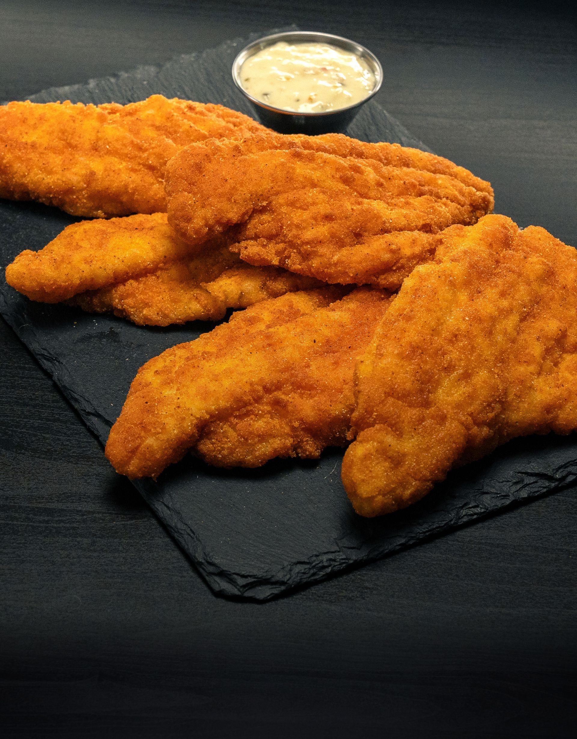 A plate of fried chicken with a side of ranch dressing