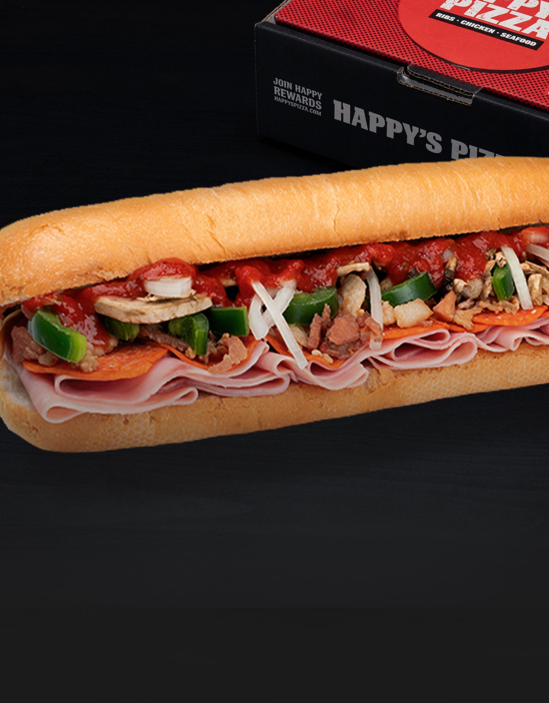 A sub sandwich is sitting on a table next to a box that says happy 's pizza