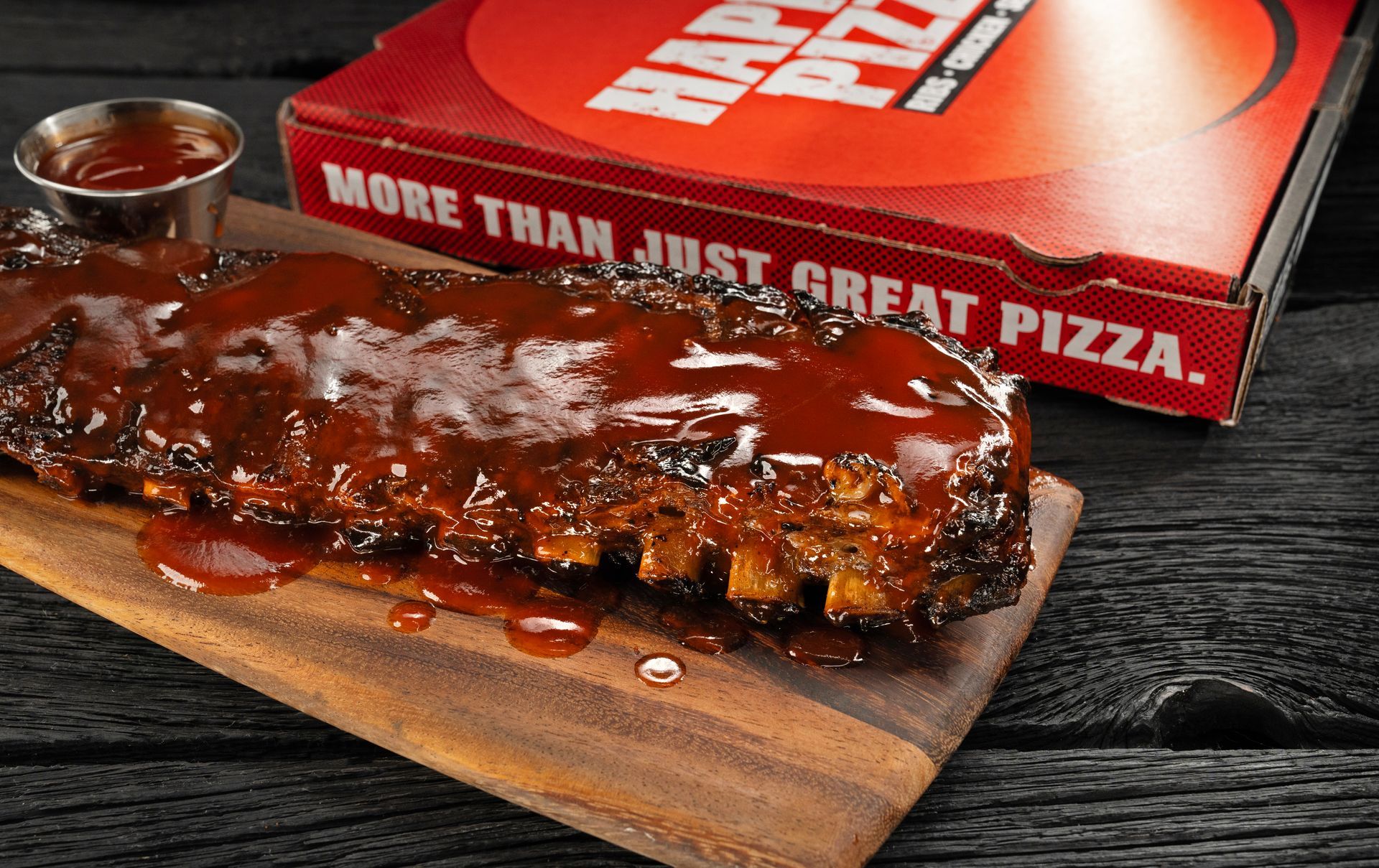 One pound of BBQ rib tips served with a side of ketchup on a black platter