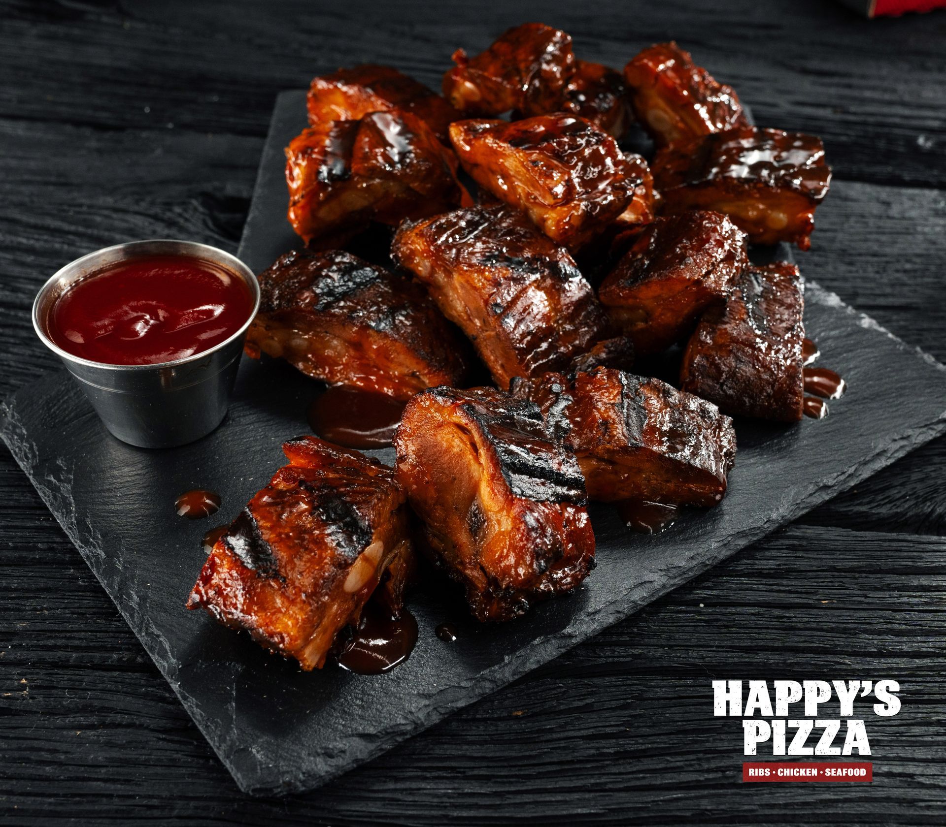 A plate of ribs with a side of ketchup from happy 's pizza