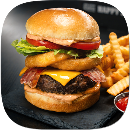 A hamburger topped with cheese, onion rings, and bacon, served with French fries and ketchup