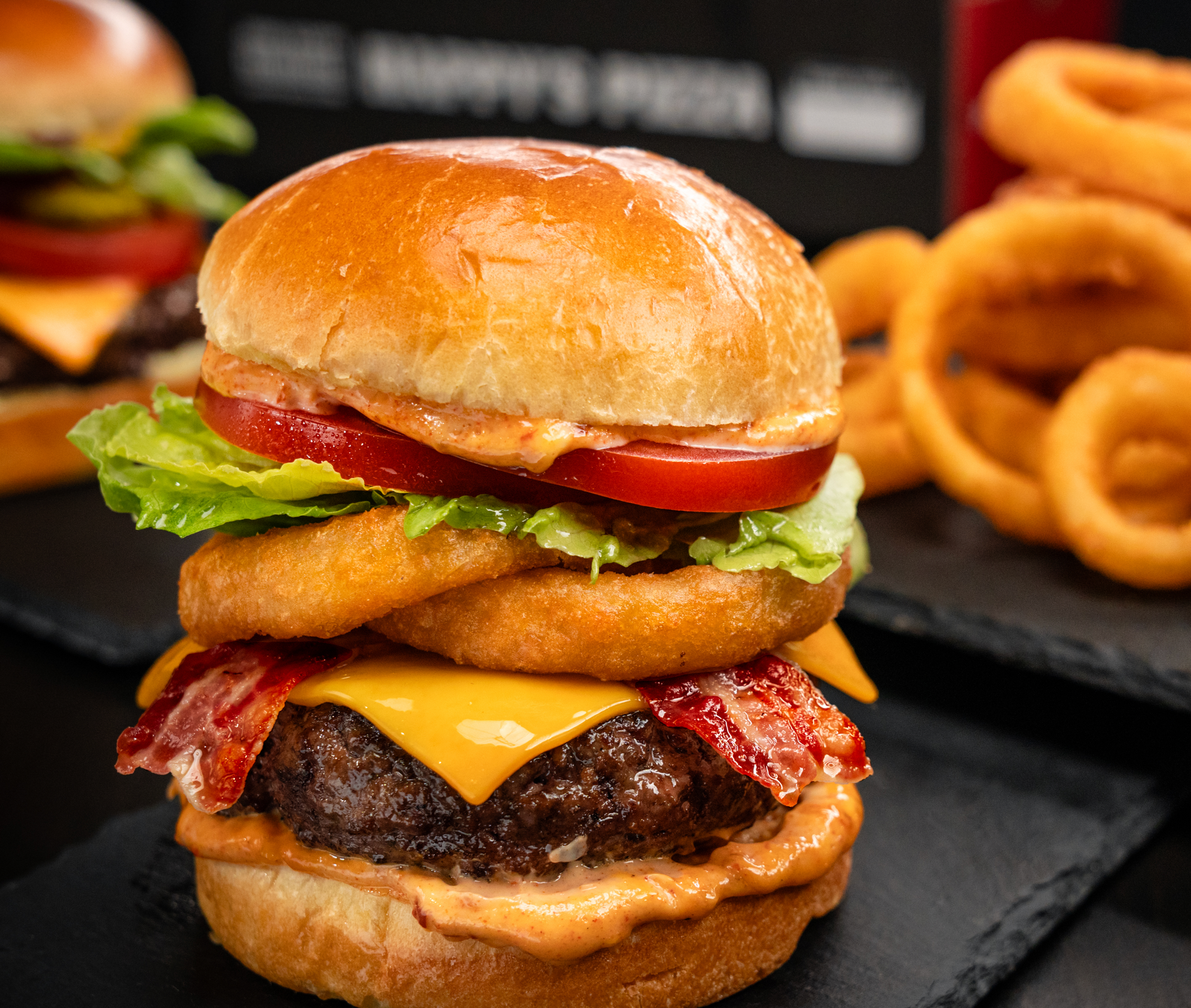 A hamburger with onion rings on top of it