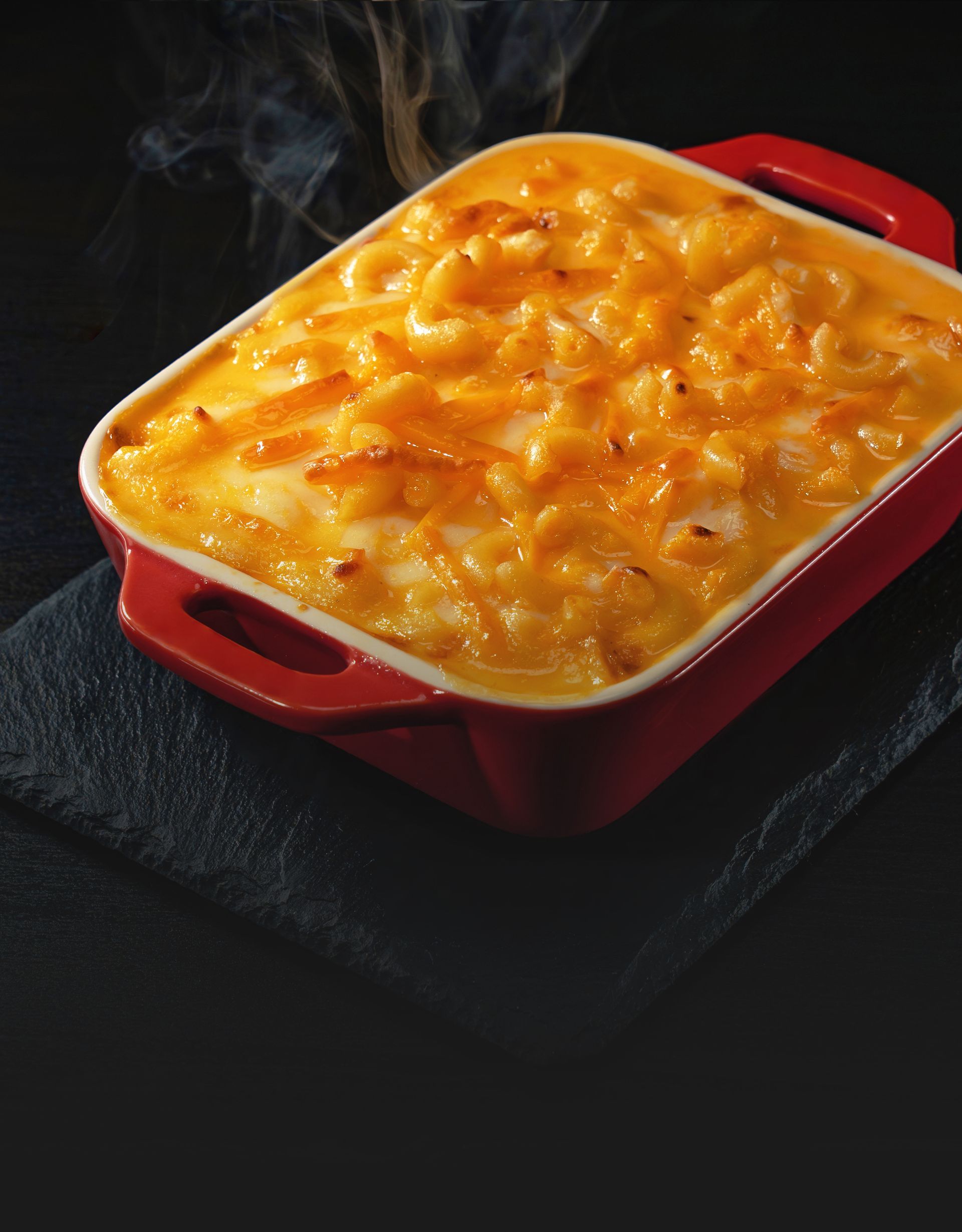 Creamy macaroni and cheese baked in a red casserole dish until golden and bubbly.