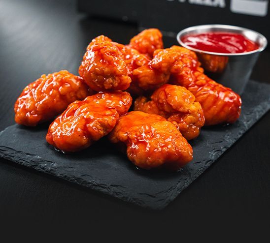 A plate of chicken nuggets with sauce on a table.
