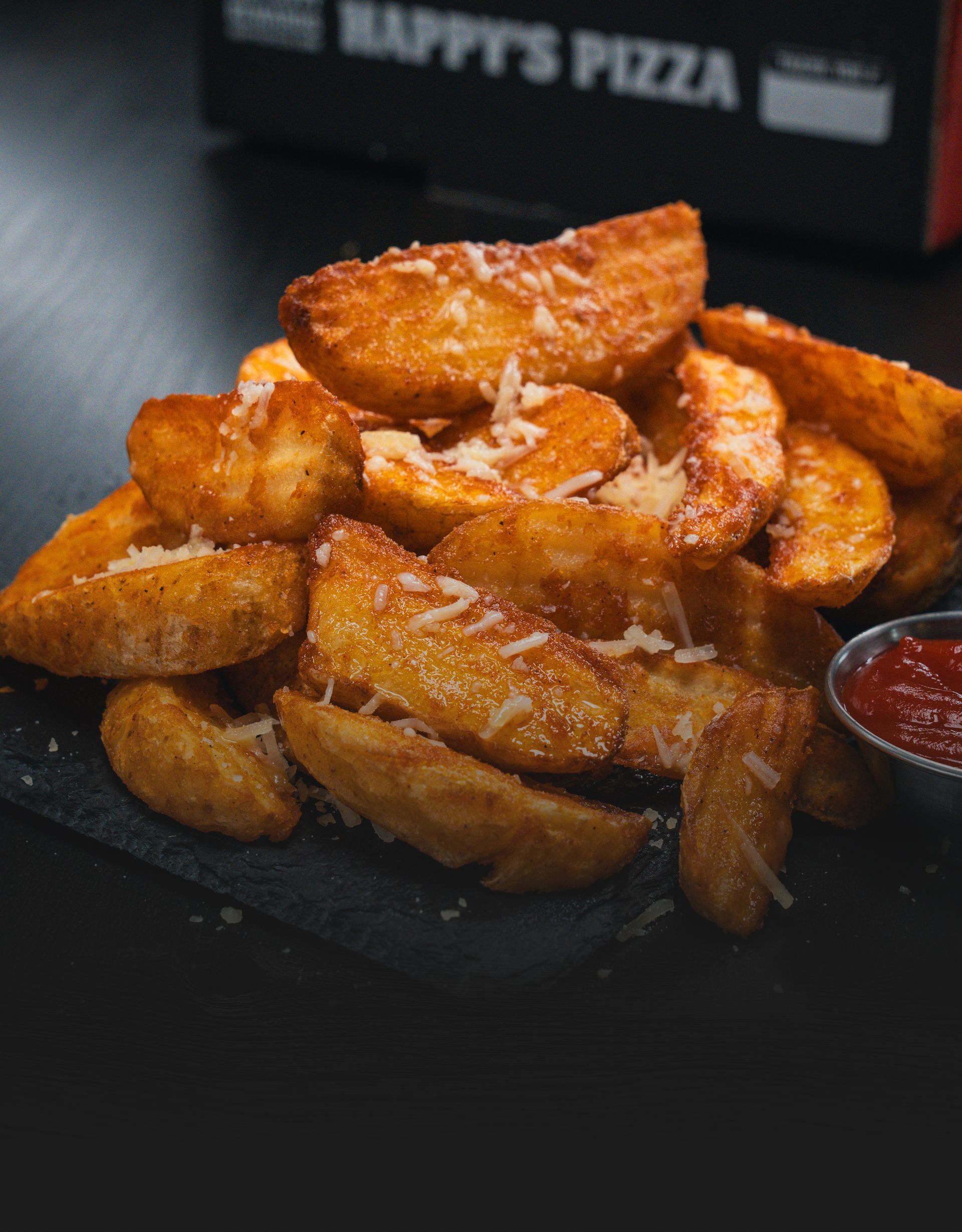 A plate of potato wedges with ketchup and cheese on a table.