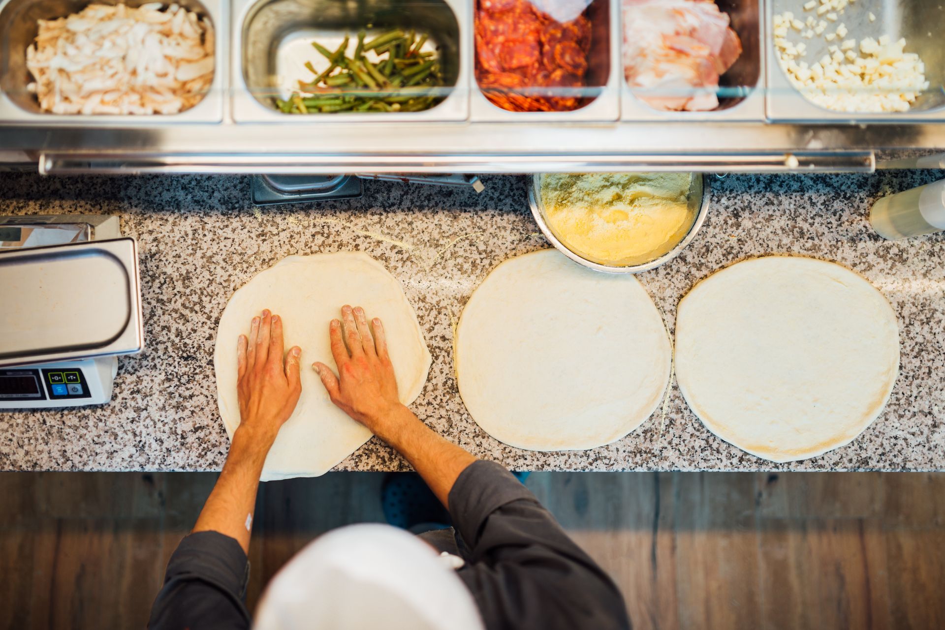 A person is kneading dough on a counter in a kitchen.