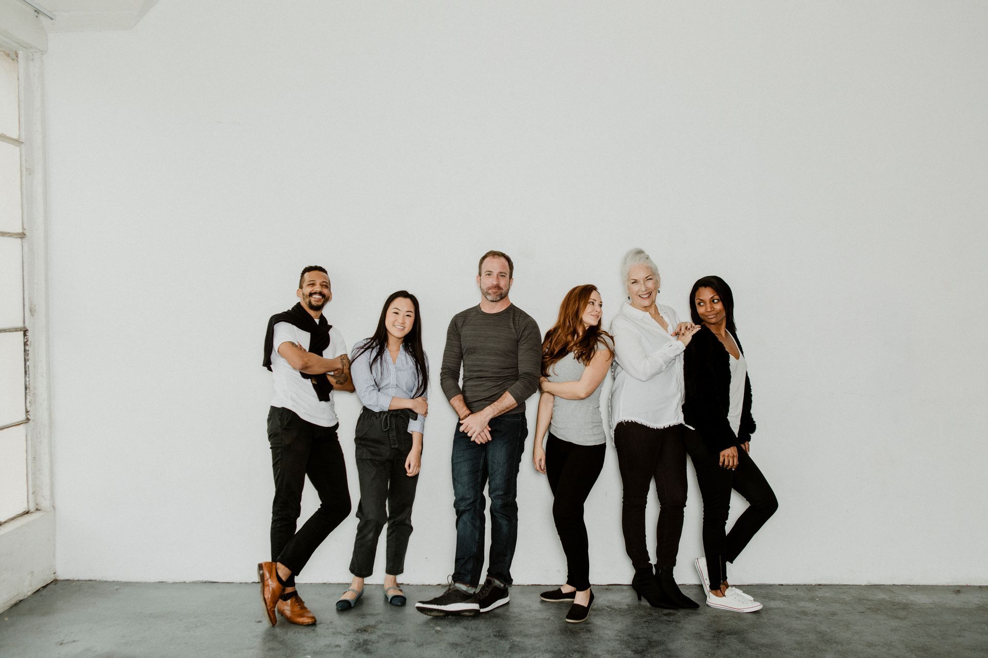 A group of people are standing next to each other in front of a white wall.