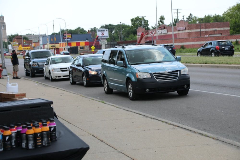 A row of cars are driving down a street.