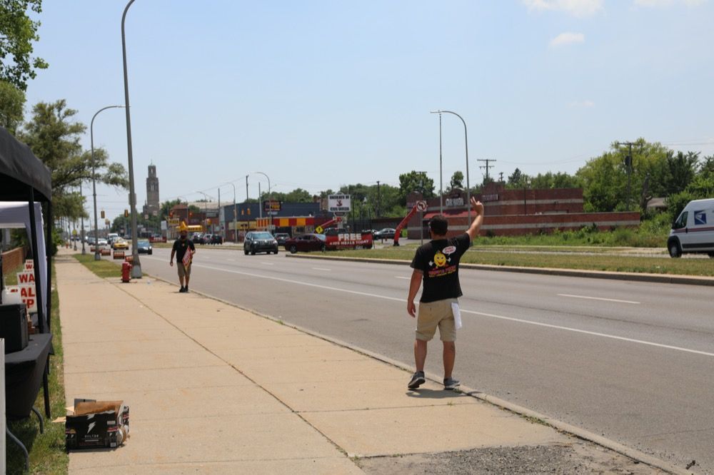 A man is standing on the sidewalk on the side of the road.