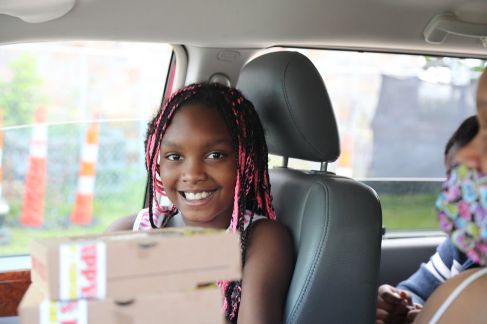 A little girl is smiling in the back seat of a car