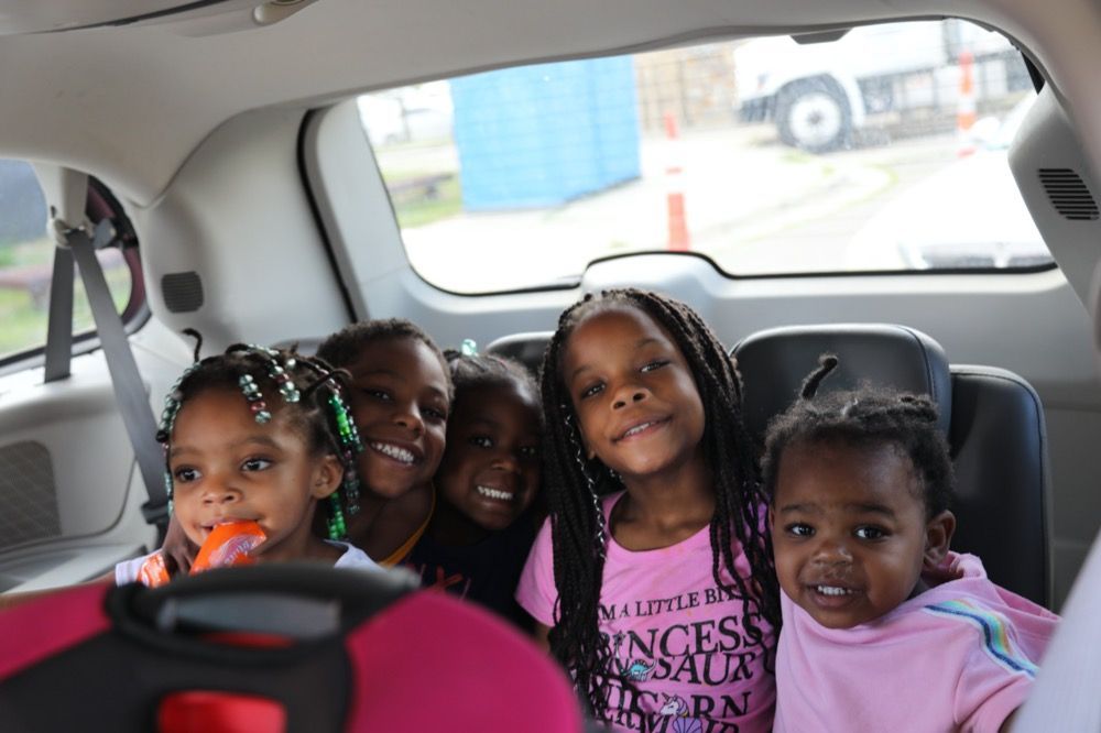 A group of young girls are sitting in the back seat of a car.