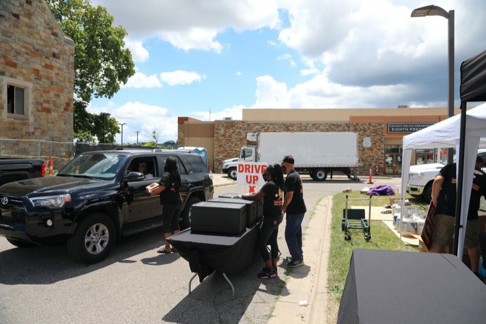 A group of people are standing in front of a drive up sign.