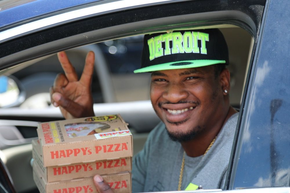 A happy Detroiter grabs a free meal for his kids from Happy's Pizza.