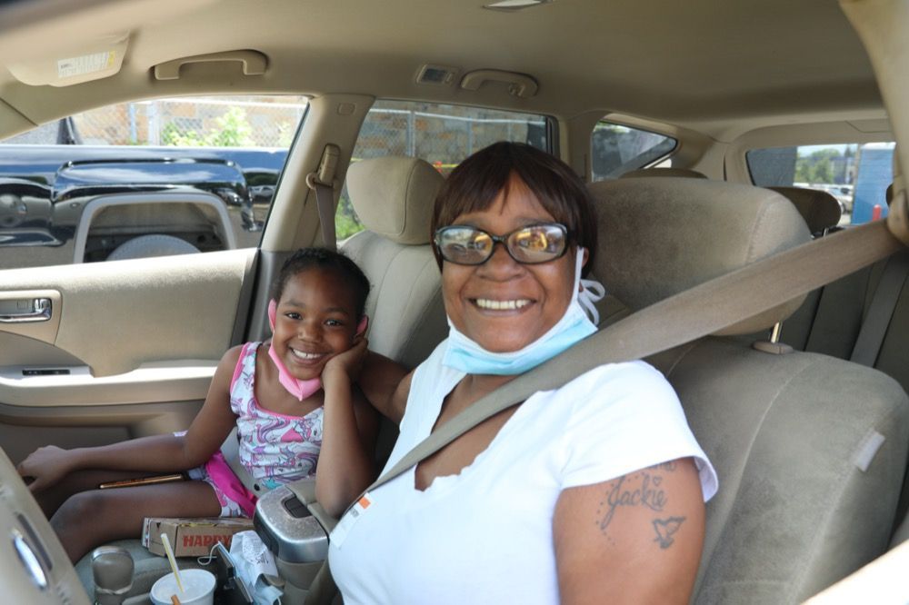 A woman and a little girl are sitting in the back seat of a car.