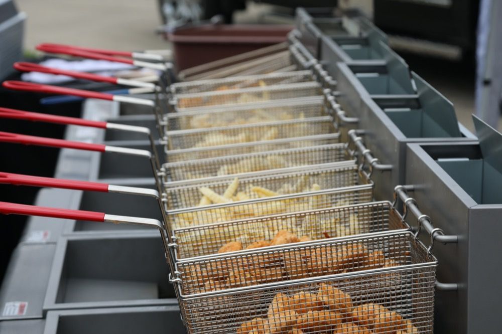 A row of fryers filled with french fries and waffle fries