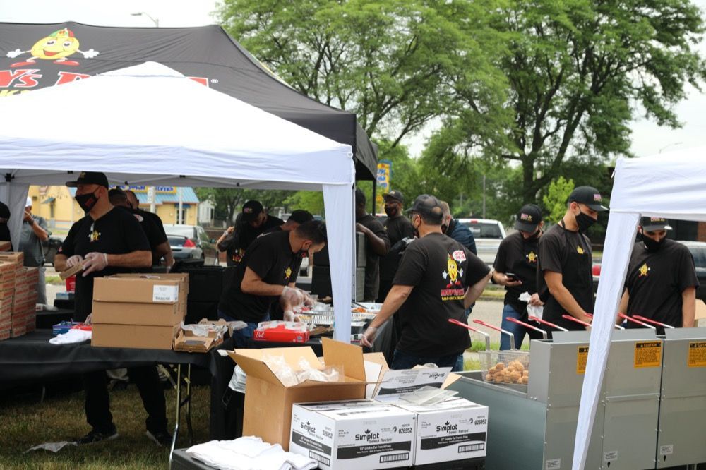 A group of people are standing around a table under a tent.