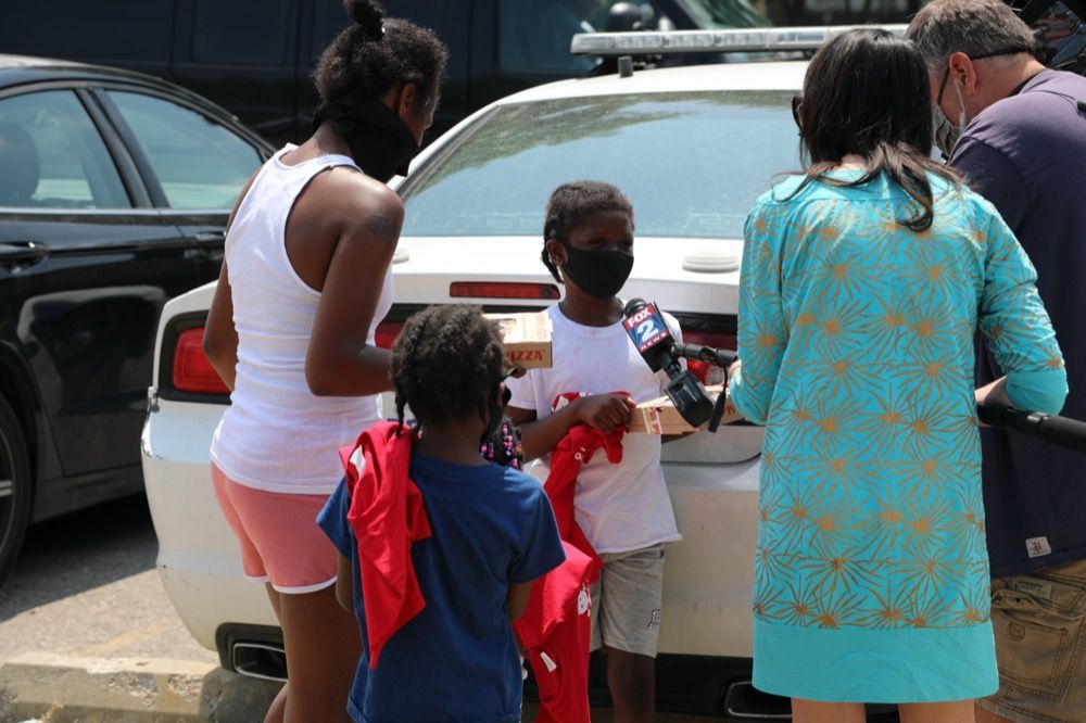 A group of people are standing around a police car.