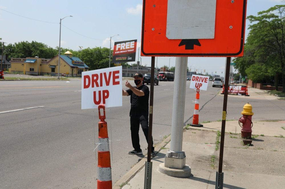 A man standing next to a sign that says drive up