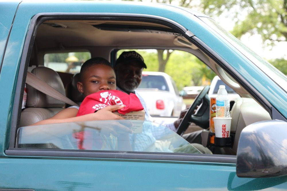 A boy in a red hat is sitting in the driver 's seat of a car.