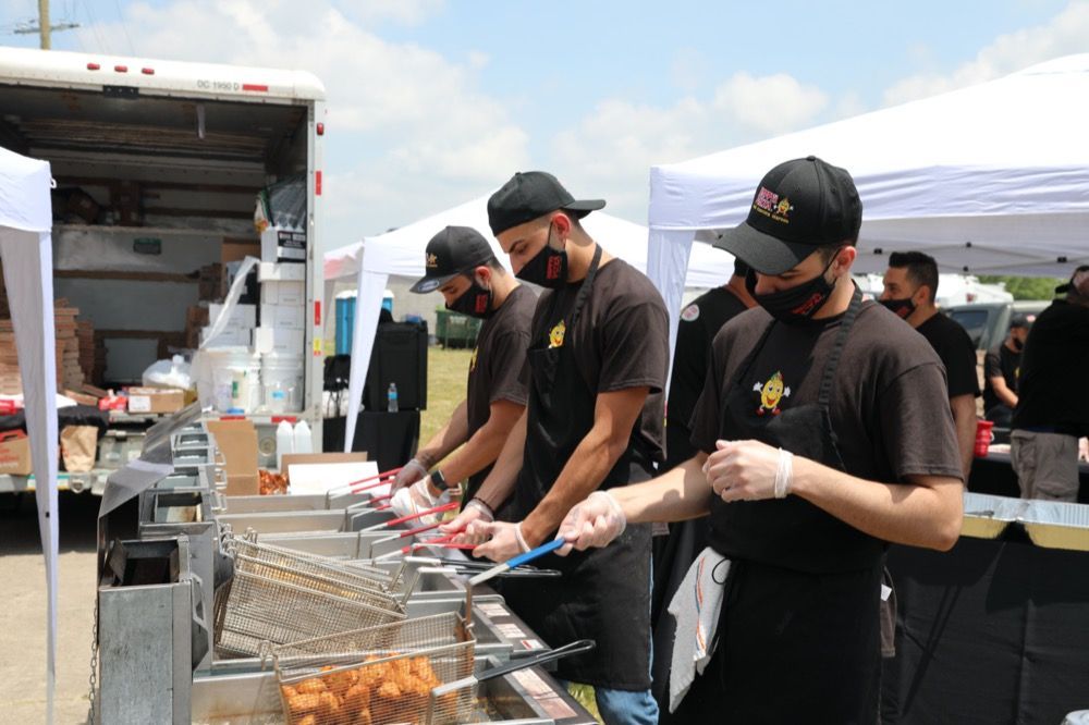 A group of men are cooking food at a food truck.
