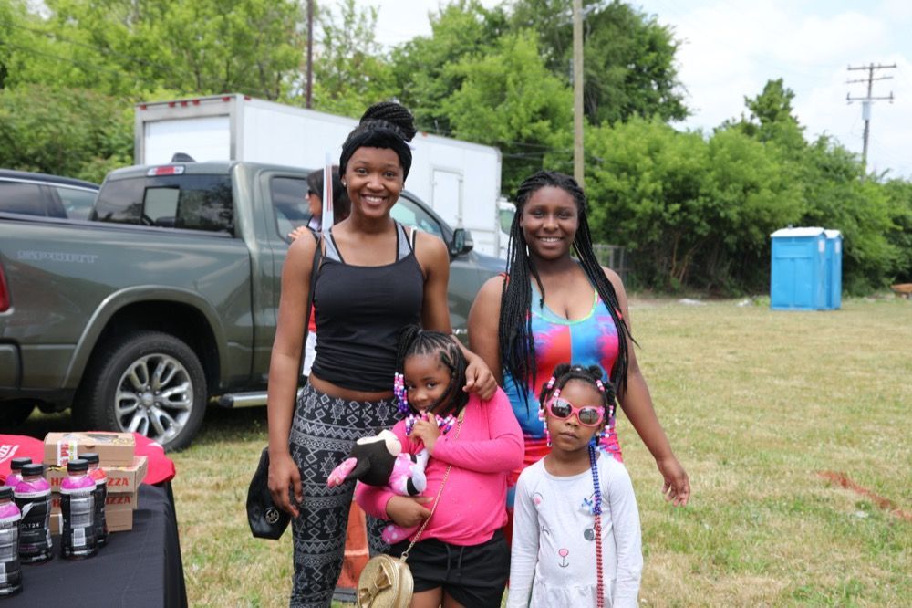 Two women and two children are standing next to each other in a field.