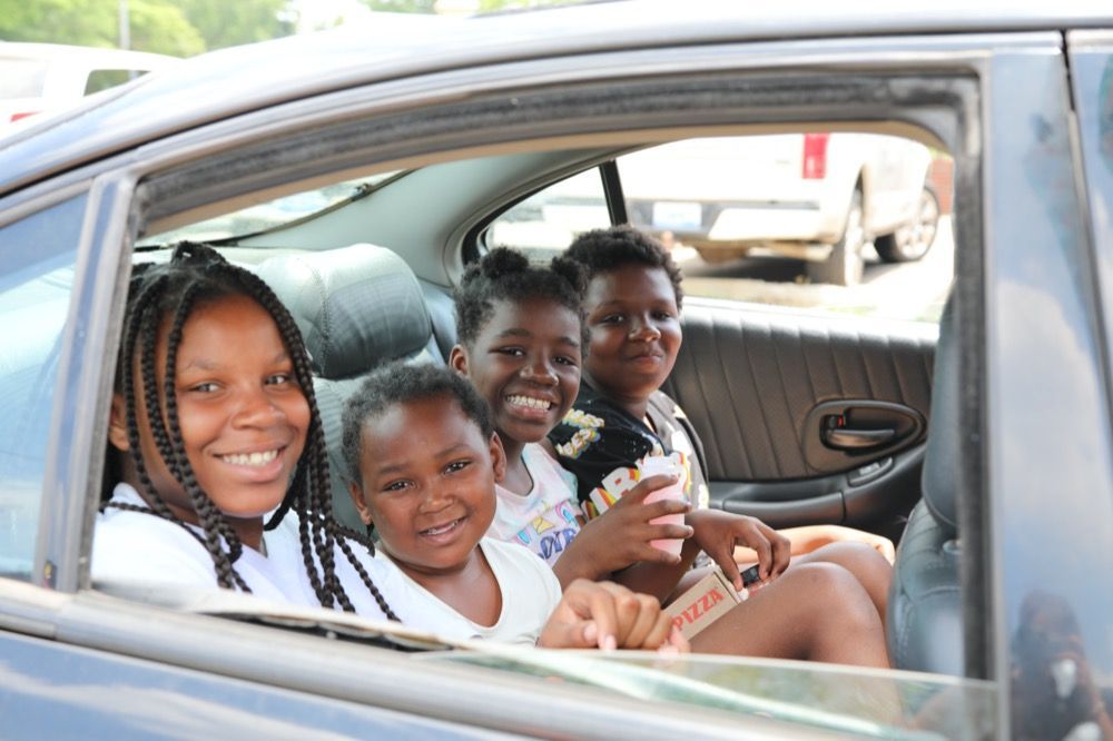 A group of children are sitting in the back seat of a car.
