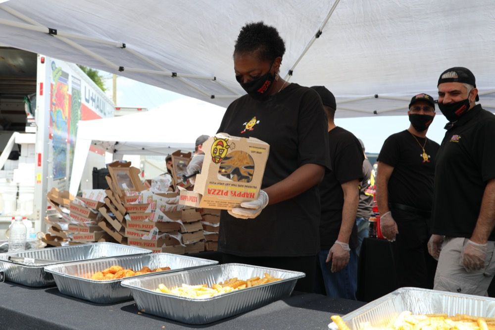 A woman wearing a mask is holding a box of pizza