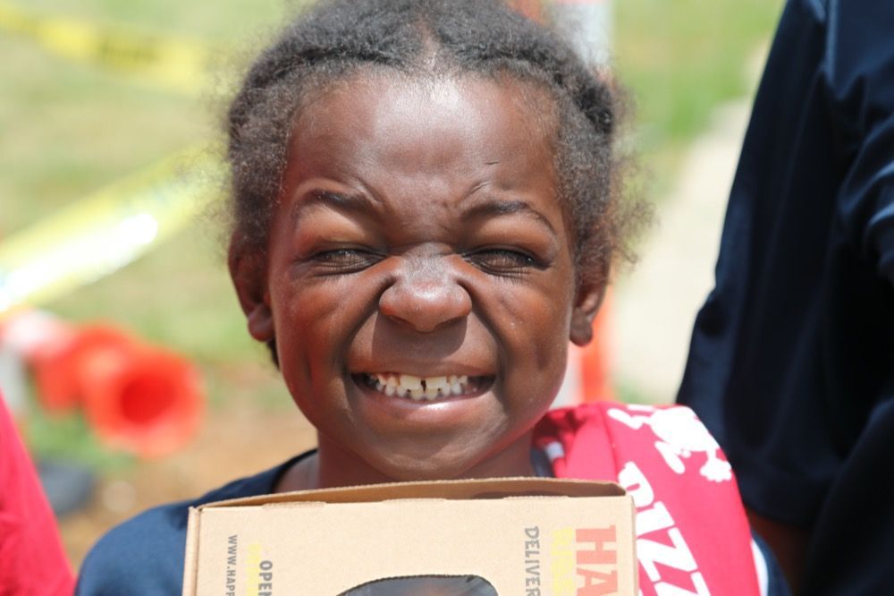 A young girl is smiling while holding a box that says hmr