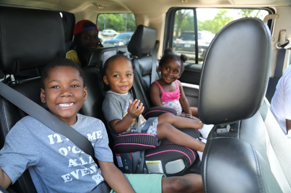 A group of children are sitting in the back seat of a car.
