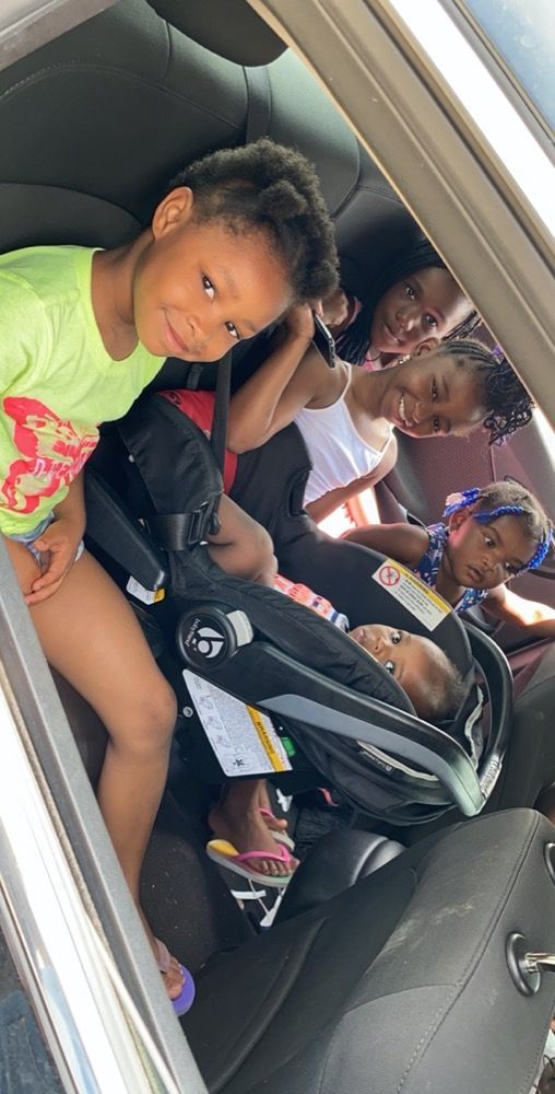 A group of children are sitting in the back seat of a car.