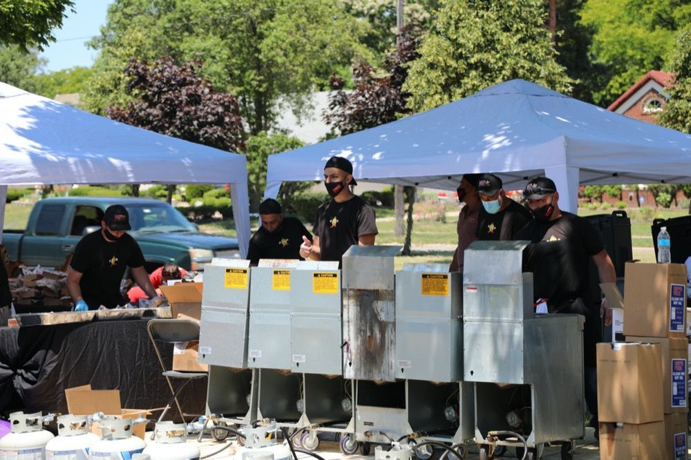 A group of people are standing around a table under a tent.