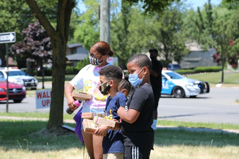 A group of children wearing face masks are standing in a park.