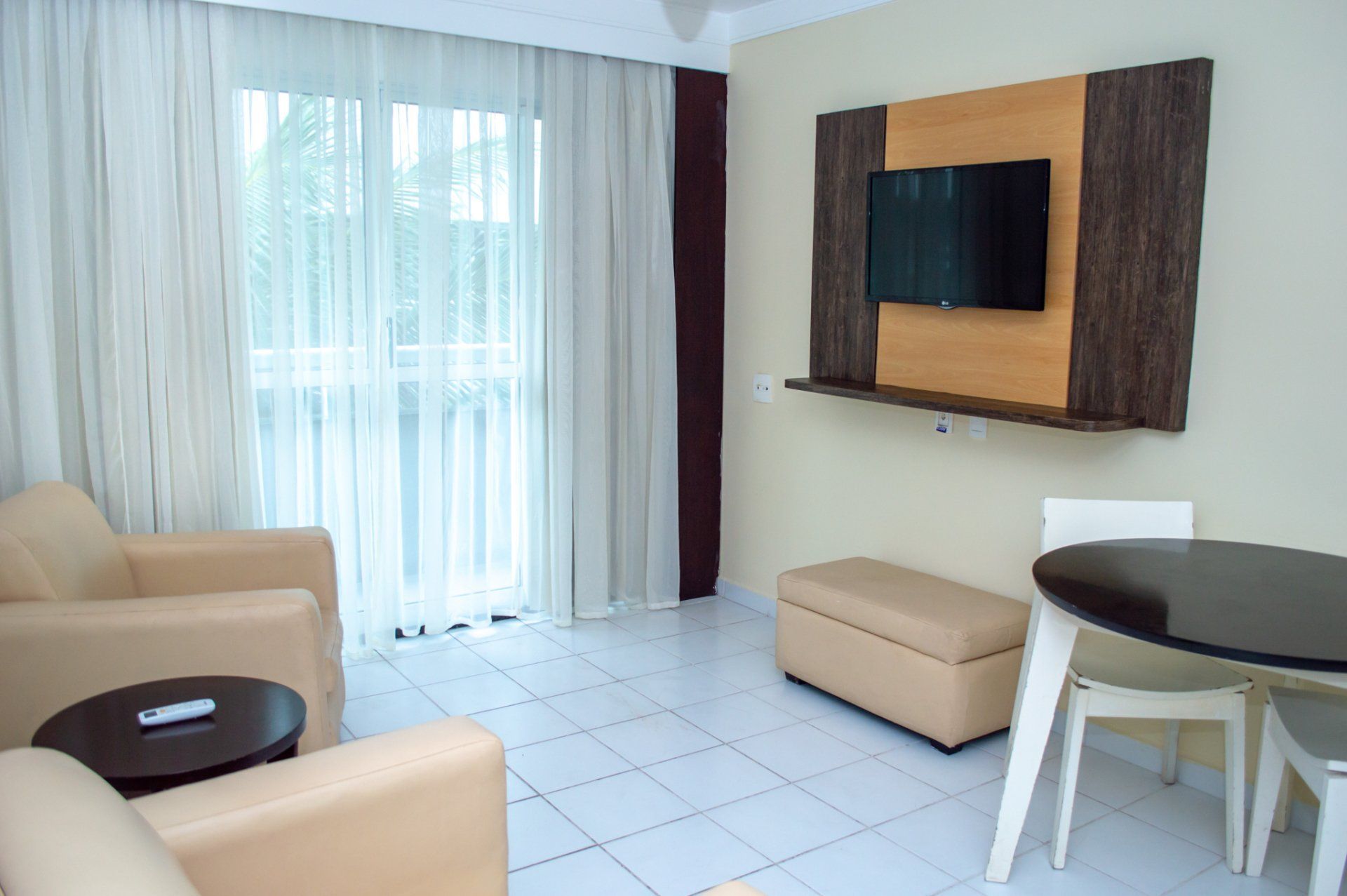 Uma sala de estar com sofá, cadeira, mesa e televisão.