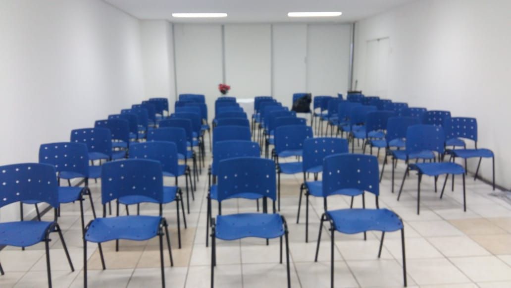 Fileiras de cadeiras azuis em uma sala com paredes brancas