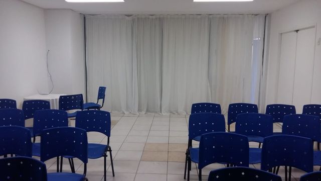 Uma sala com cadeiras azuis e cortinas brancas.