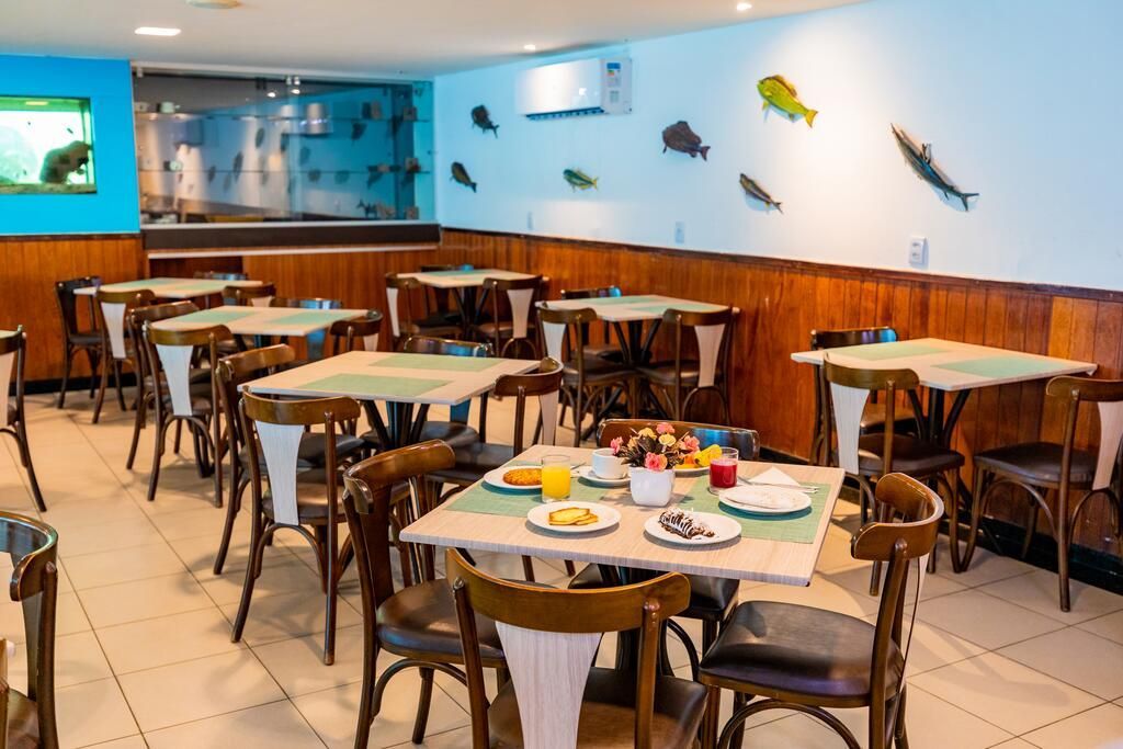 Um restaurante com mesas, cadeiras e peixes na parede.