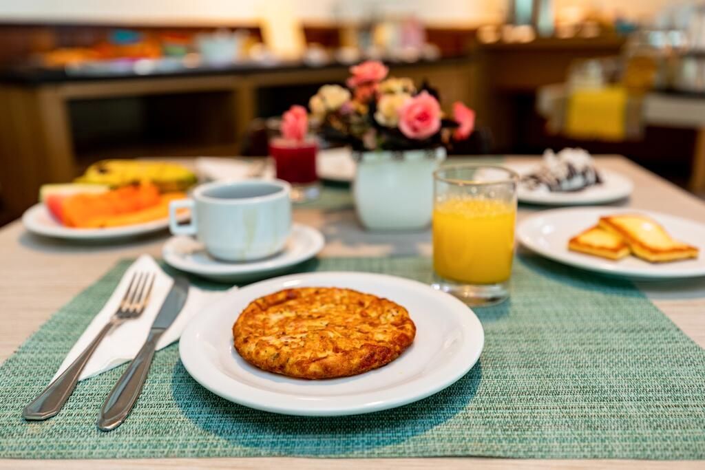 Um prato de comida está sobre uma mesa ao lado de um copo de suco de laranja.