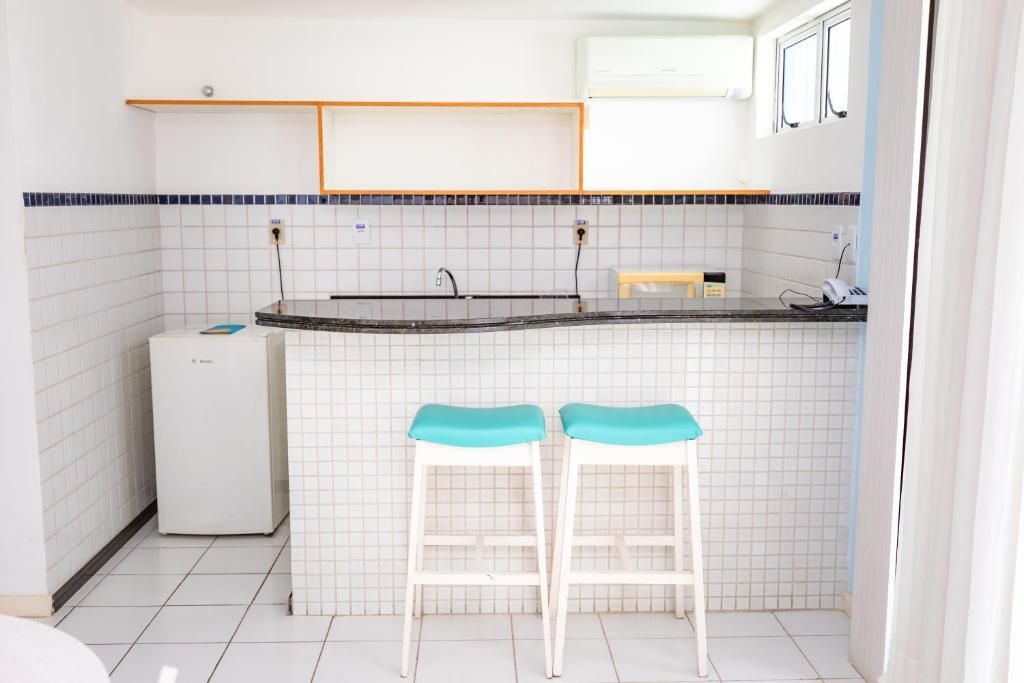 Uma cozinha com azulejos brancos e dois bancos azuis