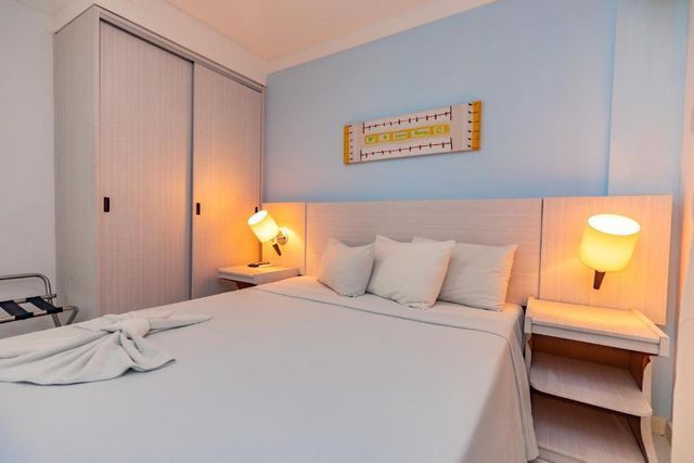 Um quarto de hotel com uma cama king size, mesas de cabeceira e uma cadeira.