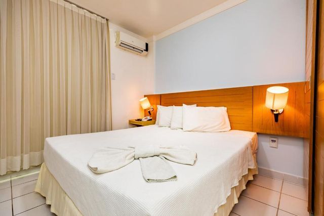 Um quarto de hotel com uma cama king size e uma janela