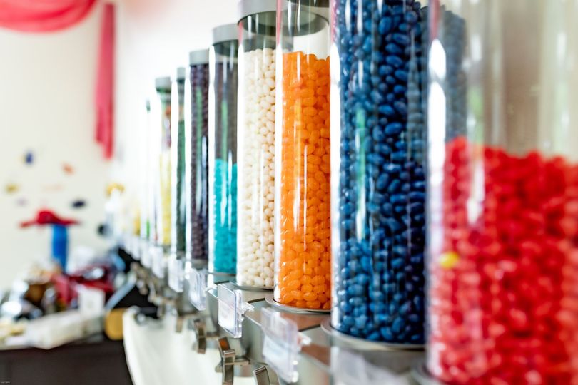 A row of jars filled with different colored candies in a candy store.