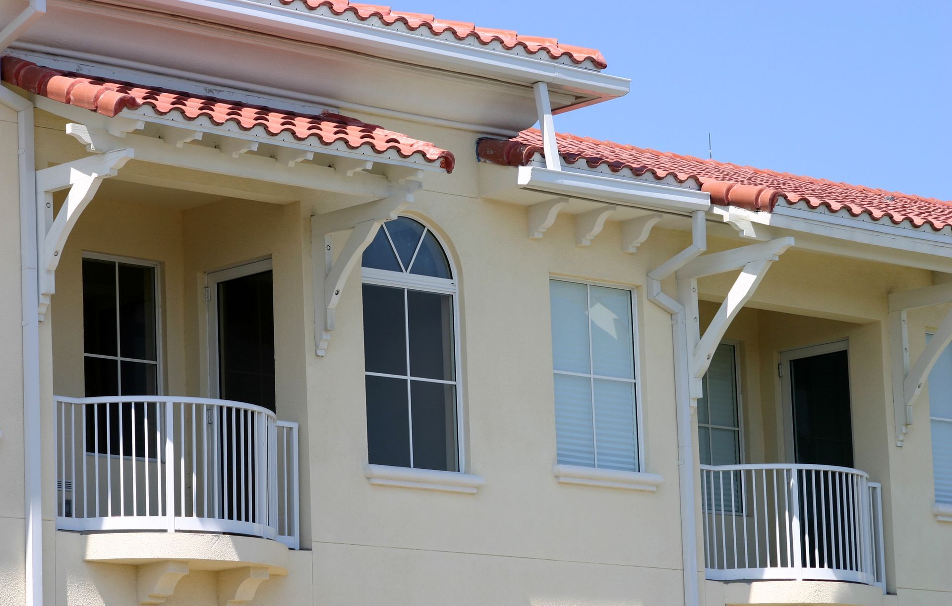 A white house with balconies and a red tile roof