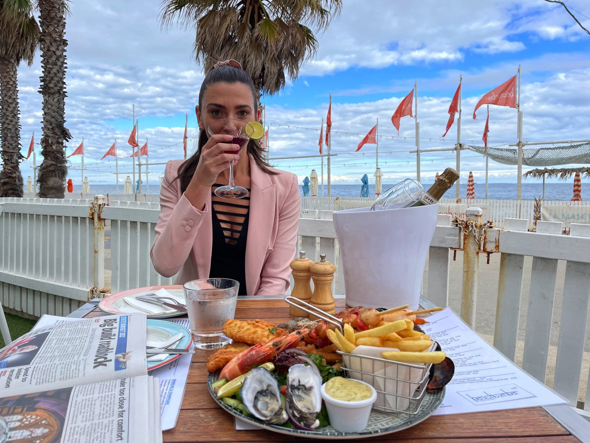 A woman is sitting at a table with a plate of food and drinking wine.