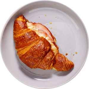 A croissant with ham and cheese on a white plate